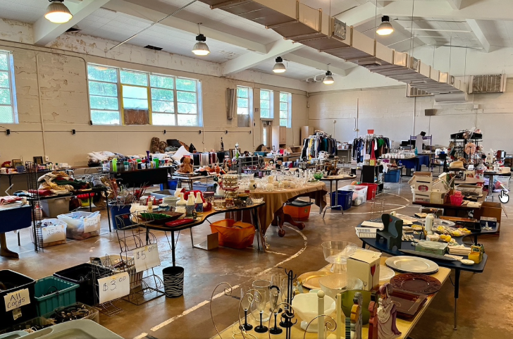 The annex interior, currently used for storage, with long tables of merchandise under high ceilings