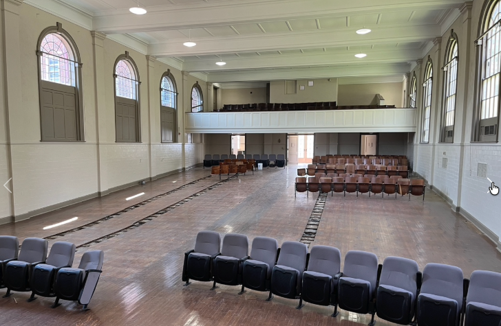 The historic Brainerd Junior High auditorium with tall arched windows, balcony, wood floor, and rows of seats